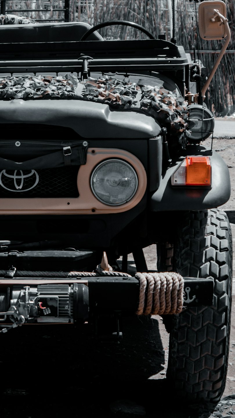 Off-road vehicle with winch and camouflage netting on hood.